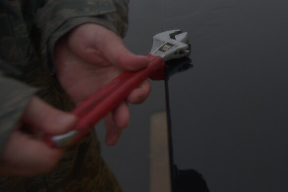 An electrical systems Airman from the 35th Civil Engineer Squadron untightens a bolt on a light panel at Misawa Air Base, Japan, Sept. 11, 2015. The Airmen removed lights on the edge-way of the flightline to prepare for the arrival of a B-52H Stratofortress, which has a wingspan long enough to potentially hit lights during landing. (U.S. Air Force photo by Senior Airman Jose L. Hernandez-Domitilo/Released)