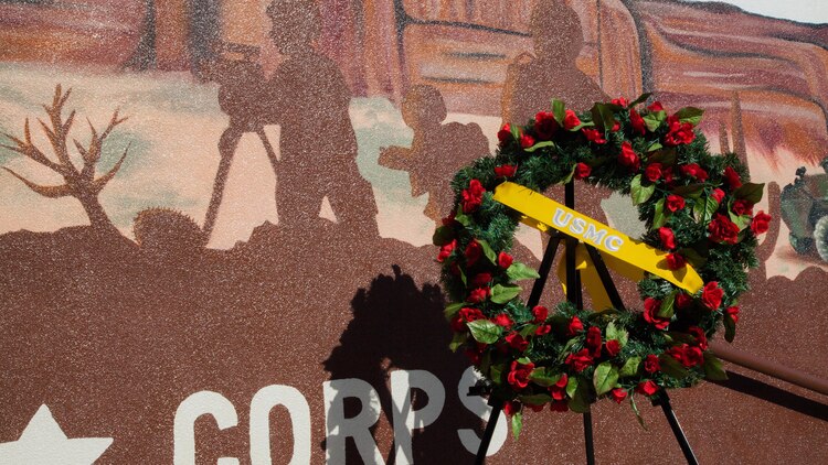 A wreath is laid beside the silhouette of a combat videographer following the unveiling of the Marine Week Phoenix mural in Scottsdale, Ariz., Sept. 12, 2015. The silhouette memorializes Lance Cpl. Jacob Hug, a Scottsdale native, who perished in a helicopter crash while the Corps was providing humanitarian assistance and disaster relief to Nepal.