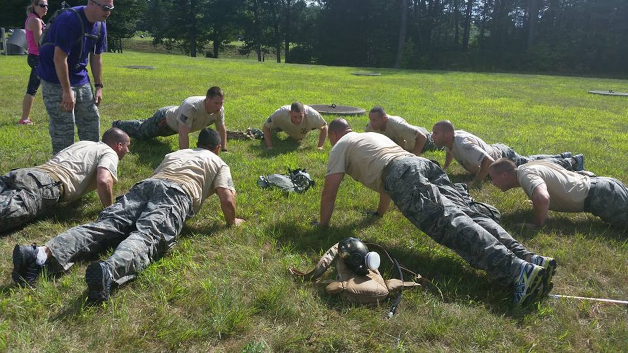 Select members of the 103rd Security Forces Squadron's CT SWAT Challenge team do group pushups as one of the many events of the challenge while team captain Staff Sgt. Michael Stearns looks on. The competitors banded up to compete in the challenge at two venues, the State Police Metacon Range in Simsbury and the MDC Reservoir in West Hartford, Conn., Sept. 17-21, 2015. (U.S. Air National Guard photos by Tech. Sgt. Jessica Roy)