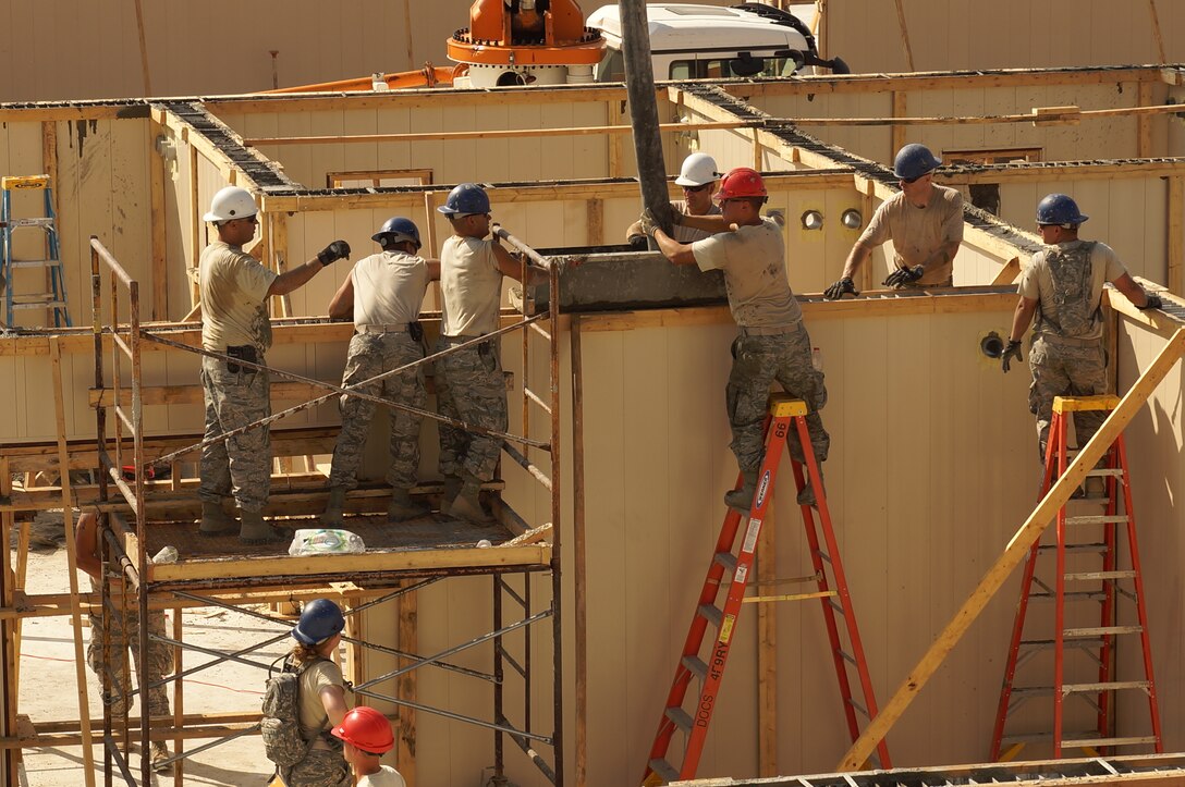 Deployed members of the 103rd Civil Engineer and 200th Red HORSE Squadrons move a concrete pumper hose down interior walls using ladders and scaffolding to avoid wall braces at Hatzor Air Base, Israel, in support of Operation JUNIPER COBRA July 20, 2015. (U.S. Air National Guard photo by Master Sgt. Robert Armstrong/RELEASED)