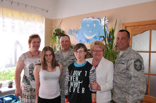 Lilita Gasjaneca, head of the Naujene Orphanage (left), Senior Master Sergeant Mark Nicolia and Technical Sargeant Richard Ryden pose for a photo with a local leader and two girls from the orphanage after donating glasses made by inmates at their civilian place of employment, Cambridge Springs Correctional Faciliity, Pennsylvania, at the orphanage, Latvia, June 29, 2015. (U.S. Air National Guard photo by Senior Airman Allyson L Manners/ Released)