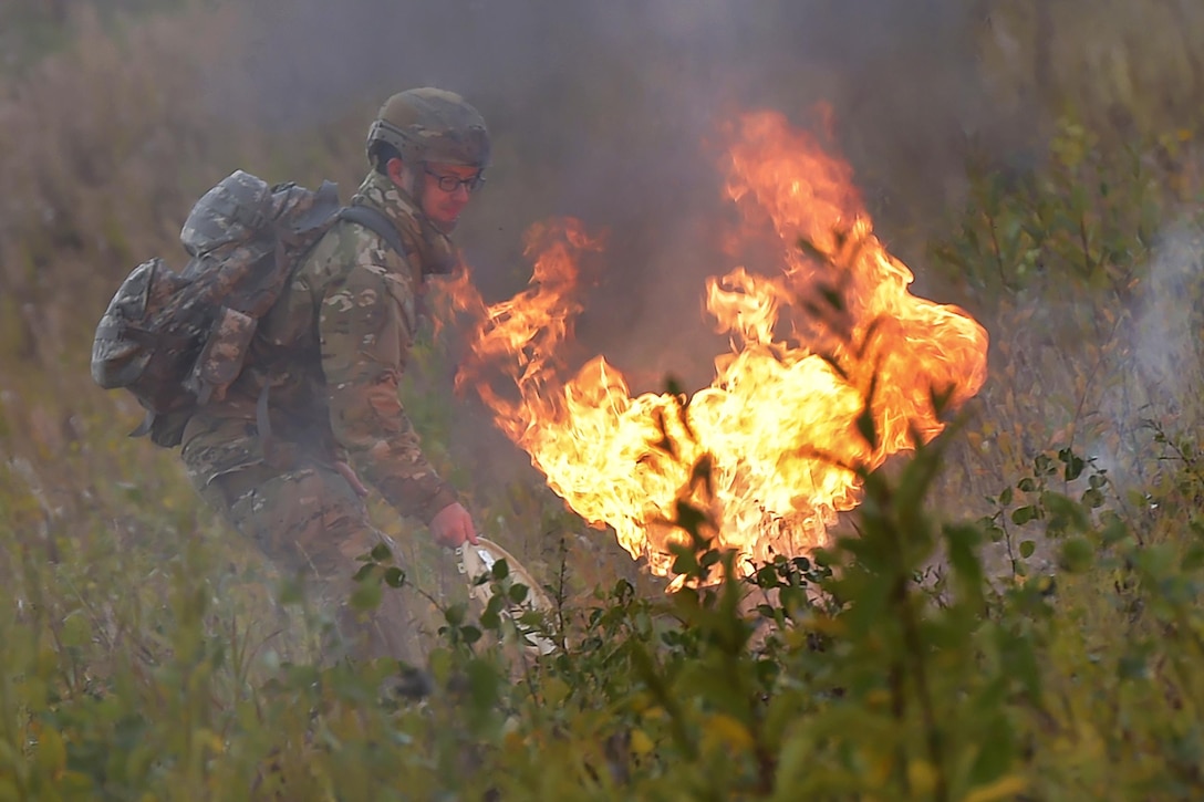 An airman tends to a smoke pot as paratroopers conduct an airborne operation from CH-47 Chinook helicopters over Malemute drop zone on Joint Base Elmendorf-Richardson, Alaska, Sept. 10, 2015. The paratroopers are assigned to U.S. Army Alaska. U.S. Air Force photo by Justin Connaher