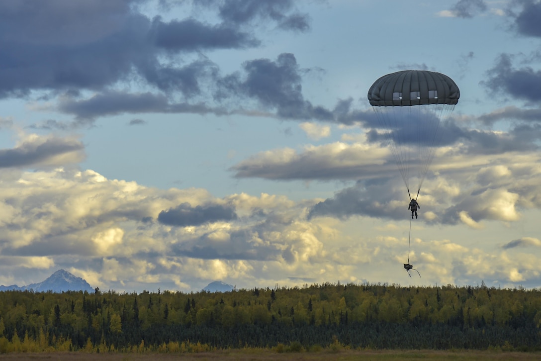 A paratrooper lowers his rucksack as he prepares to land while conducting an airborne operation over Malemute drop zone on Joint Base Elmendorf-Richardson, Alaska, Sept. 10, 2015. U.S. Air Force photo by Justin Connaher
