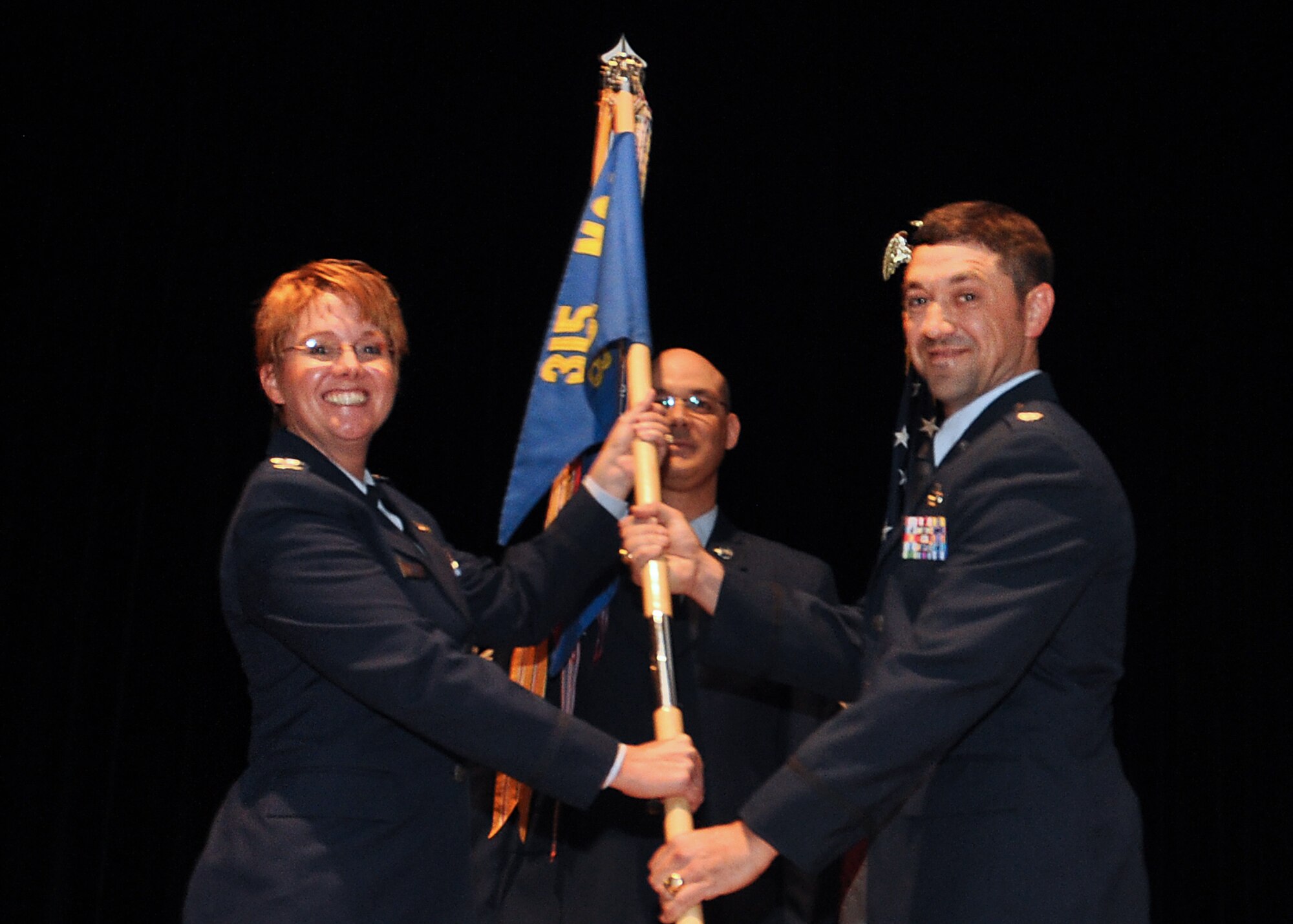 Col. Cherie Roff, 315th Mission Support commander, passes the guidon to Lt. Col. Wesley Maxwell, new 38th Aerial Port Squadron commander, during an change of command ceremony at Joint Base Charleston, S.C. Sept. 13, 2015. (U.S. Air Force Photo by Senior Airman Tom Brading)