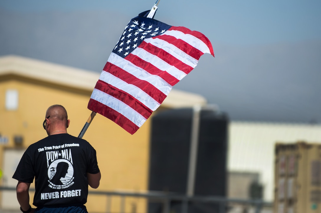 U.S. Air Force Chief Master Sgt. Matt Grengs carries the U.S. flag while participating in a run to honor prisoners of war and those missing in action on Bagram Airfield, Afghanistan, Sept. 3, 2015. Grengs is assigned to the 455th Air Expeditionary Wing. U.S. Air Force photo by Tech. Sgt. Joseph Swafford