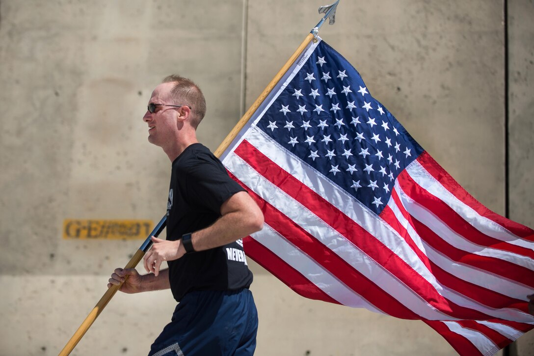 U.S. Air Force Maj. Brian Yates carries the U.S. flag while participating in a run to honor prisoners of war and those missing in action on Bagram Airfield, Afghanistan, Sept. 3, 2015. Yates is the deputy commander of the 455th Air Expeditionary Wing. U.S. Air Force photo by Tech. Sgt. Joseph Swafford