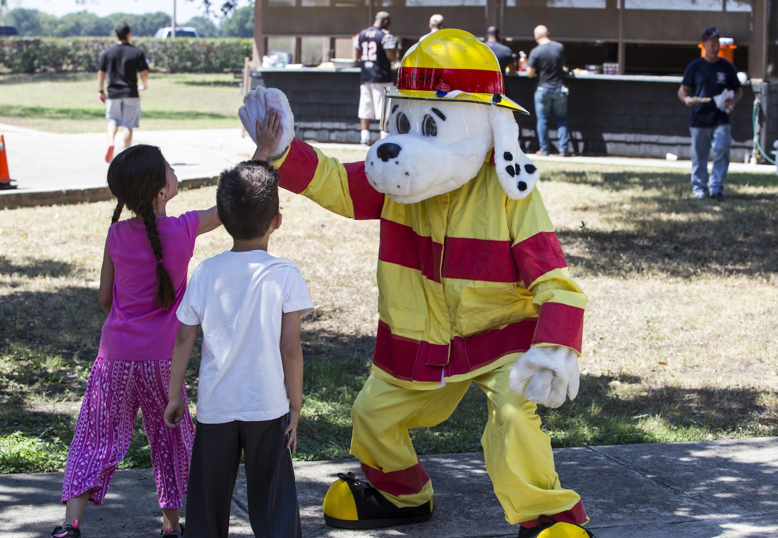 Sparky the Fire Dog high-fives children attending the 2015 Battle of the Badges Sept. 12 at Eberle Park at Joint Base San Antonio-Randolph. Family members and friends of competitors attended the event to cheer them on and learn about first responder missions that take place across JBSA.