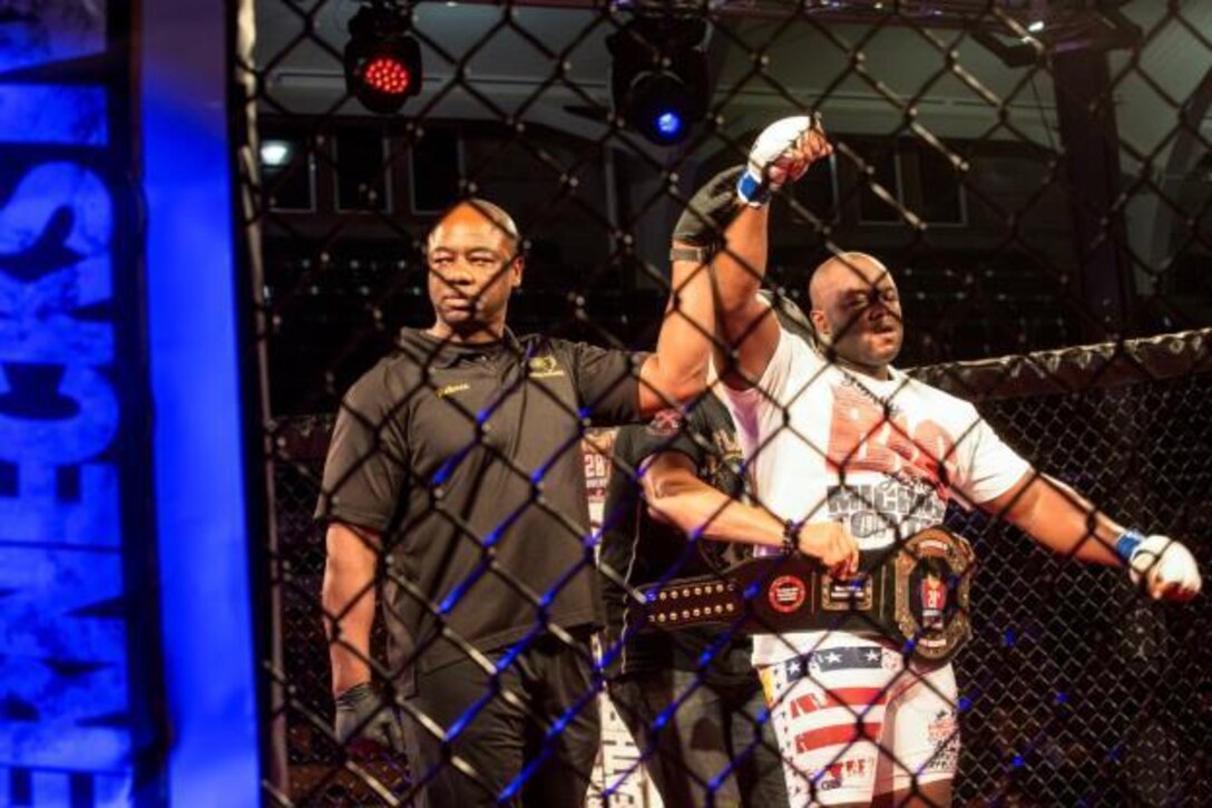 Leroy Johnson claims victory over Arnold Adams in the heavyweight title fight during Leatherneck IV, MMA Fight Night Live aboard Camp Lejeune, N.C., Sept. 2, 2015. Marines gathered at Goettge Memorial Field House to watch nine professional fights and meet special guest five-time UFC Champion and UFC Hall of Famer, Randy Couture. (U.S. Marine Corps photo by Lance Cpl. Aaron Kane Fiala/Released)