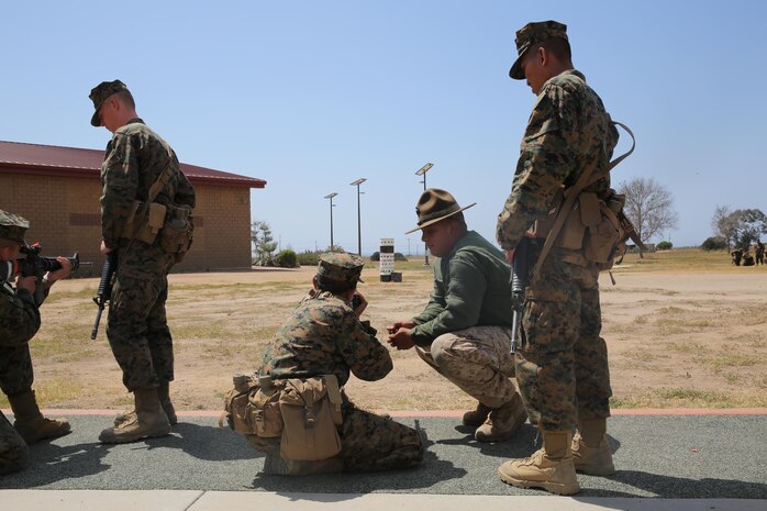 Sgt. Andrew L. Vega, primary marksmanship instructor, Weapons and Field Training Battalion, Marine Corps Base Camp Pendleton, Calif., assists a recruit of Echo Company, 2nd Recruit Training Battalion, with achieving a successful kneeling firing position during Grass Week, Sept. 9. The PMIs corrected the recruits’ firing positions to ensure the recruits were comfortable and prepared to conduct live firing the following week . Today, all males recruited from west of the Mississippi are trained at MCRD San Diego. The depot is responsible for training more than 16,000 recruits annually. Echo Company is scheduled to graduate Oct. 30. 