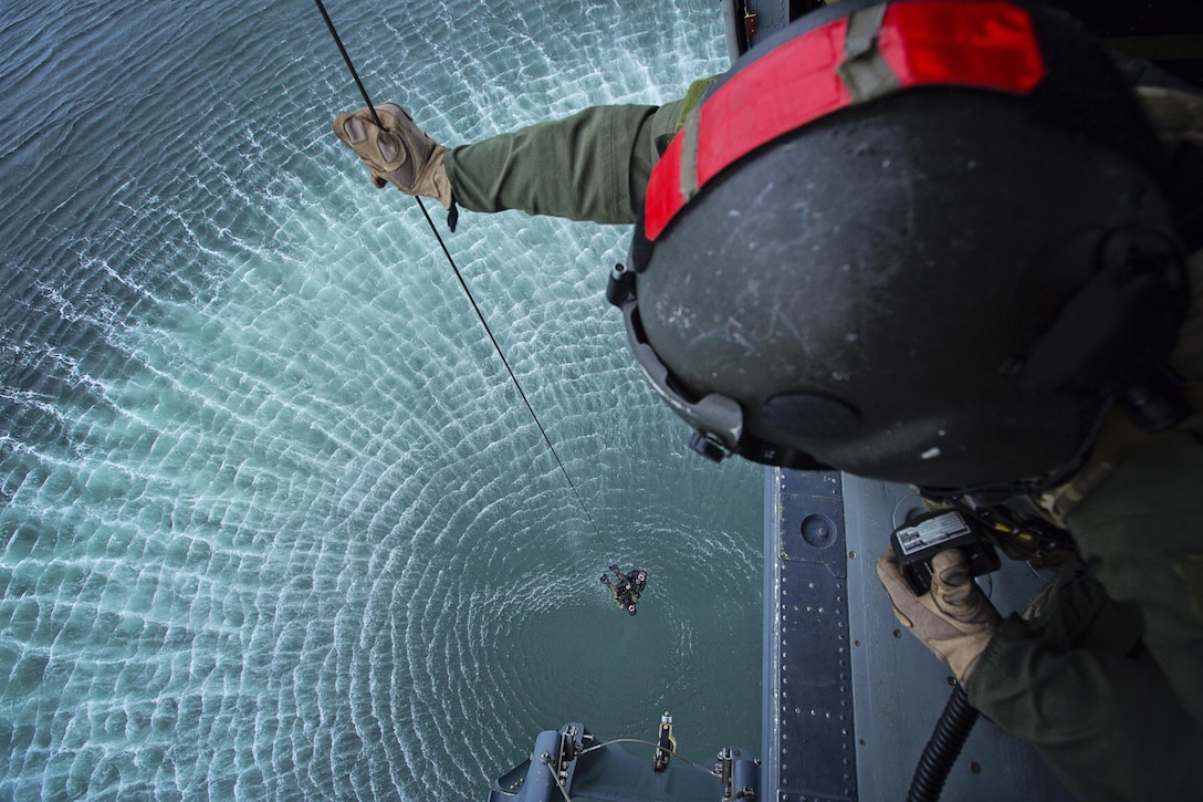 Tech. Sgt. Dave Torrance, 210th Rescue Squadron Special Mission Aviator with the Alaska Air National Guard’s HH-60 Pave Hawks, mans the hoist cable system during a training mission above Homer, Alaska. The cable hoist system is used to lower pararescuemen to treat and rescue potential victims when the weather or terrain does not allow for the helicopter to land. Three boaters were rescued Sept. 11, 2015, by a similar system.