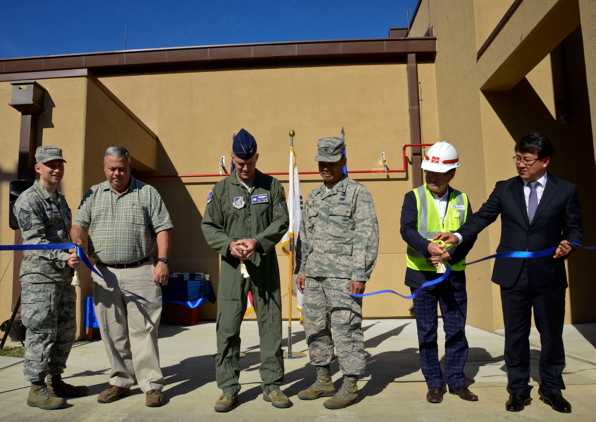 Col. Andrew Hansen, 51st Fighter Wing commander (middle left), cuts the ribbon in front of the new 51st Maintenance Squadron precision measurement equipment laboratory on Osan Air Base, Republic of Korea, Sept. 9, 2015. The new facility was built to correct major environmental control system and floor space deficiencies noted in every evaluation by the Air Force Metrology and Calibration certification team since 1994. (U.S. Air Force photo/Senior Airman Kristin High)