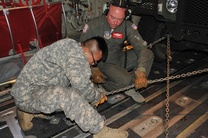 Army Spc. Bach Dong, a mechanic, both in the 890th Engineering Battalion, and Air Force Master Sgt. Joshua Stanton, a loadmaster in the 815th Airlift Squadron work together to tie down a military ambulance into the cargo area of a C-130J aircraft.  The Air Force Reserve, the Air National Guard and the Army National Guard teamed up for a joint training scenario called Joint Conquest here and at the Gulfport Combat Readiness Training Center, Mississippi Sept. 11-13.