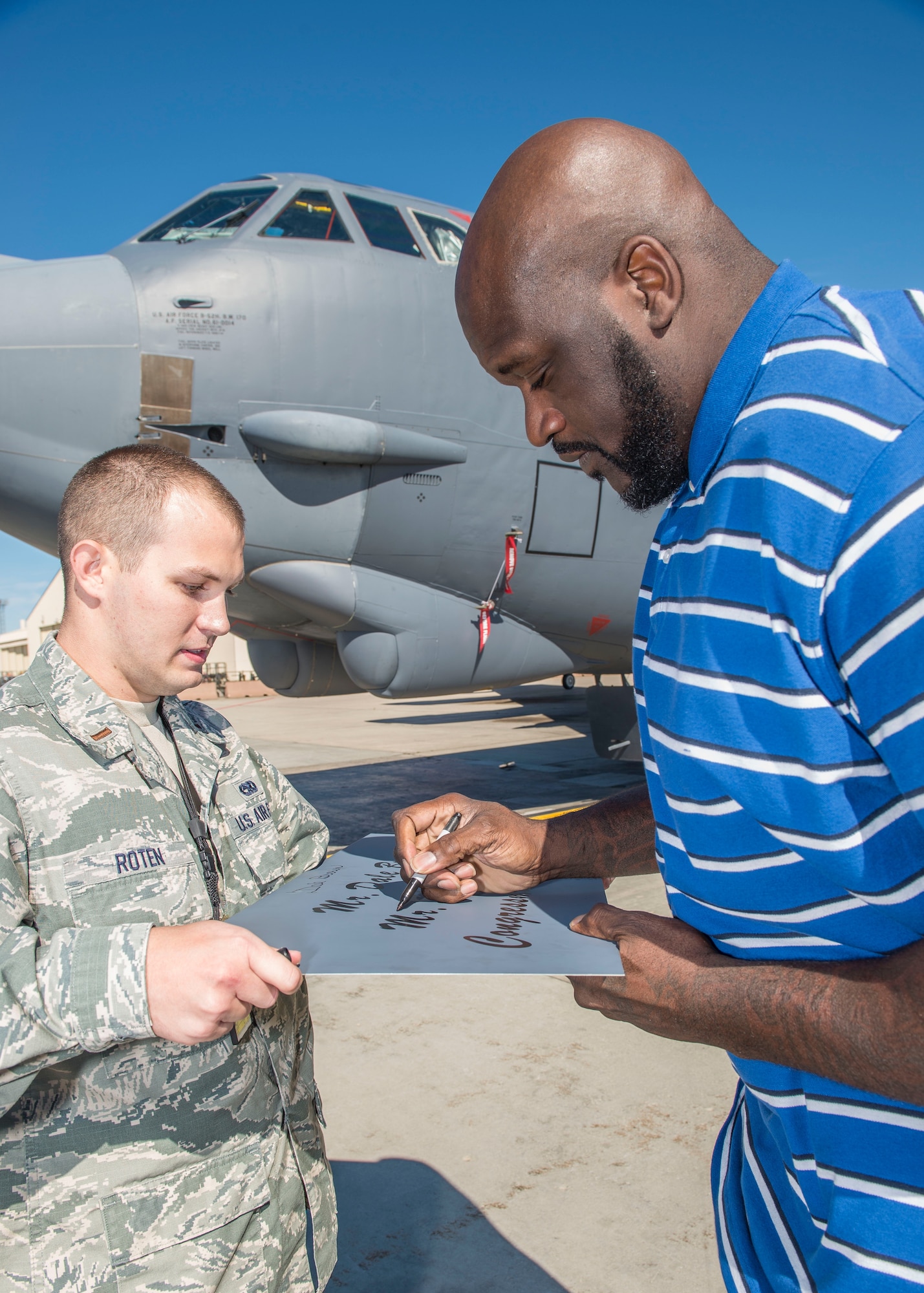 Shaquille O’Neil, former professional basketball player, signs a name plaque held by 2nd Lt. Tyler Roten, 5th Maintenance Squadron fabrication flight commander, at Minot Air Force Base, N.D., September 8, 2015.  O’Neil spoke to Airmen at the base theater about his father, a former Army drill sergeant, and how the military’s values shaped his success. (U.S. Air Force photo/ Airman 1st Class Justin T. Armstrong)