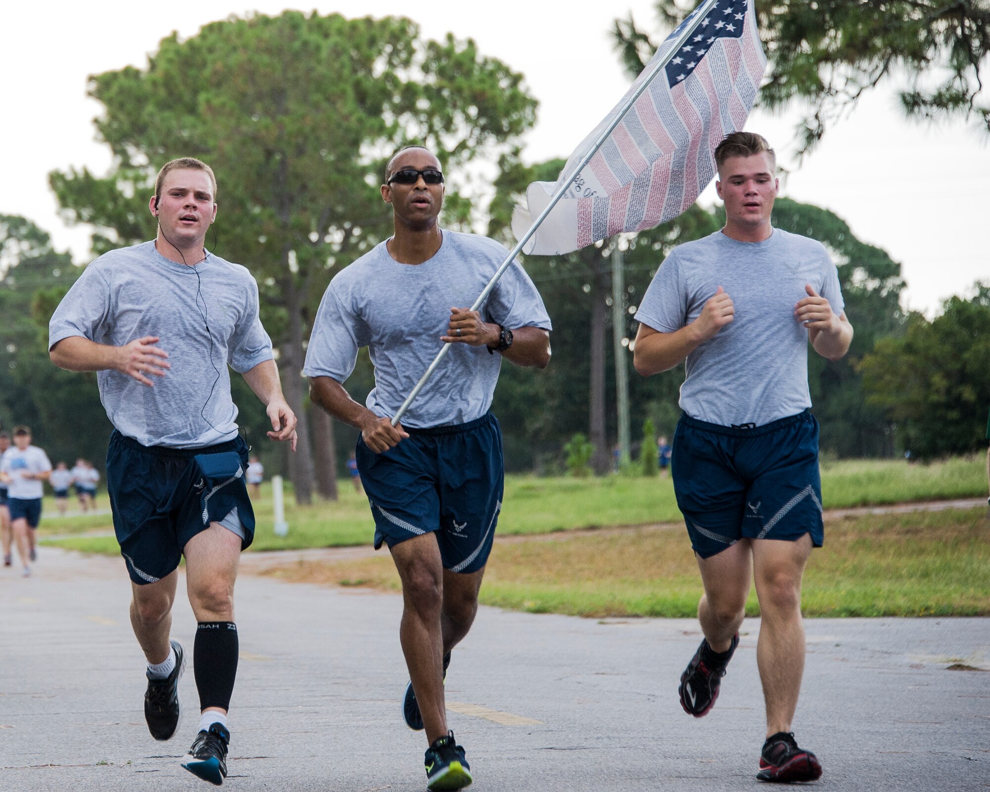 An Airmen carries a flag of honor accompanied by fellow Airmen during the 9/11 Memorial 3-Mile Run/Walk at Eglin Air Force Base, Fla. Sept. 11. More than 535 runners participated in the run to remember the events of 9/11. (U.S. Air Force photo/Ilka Cole)