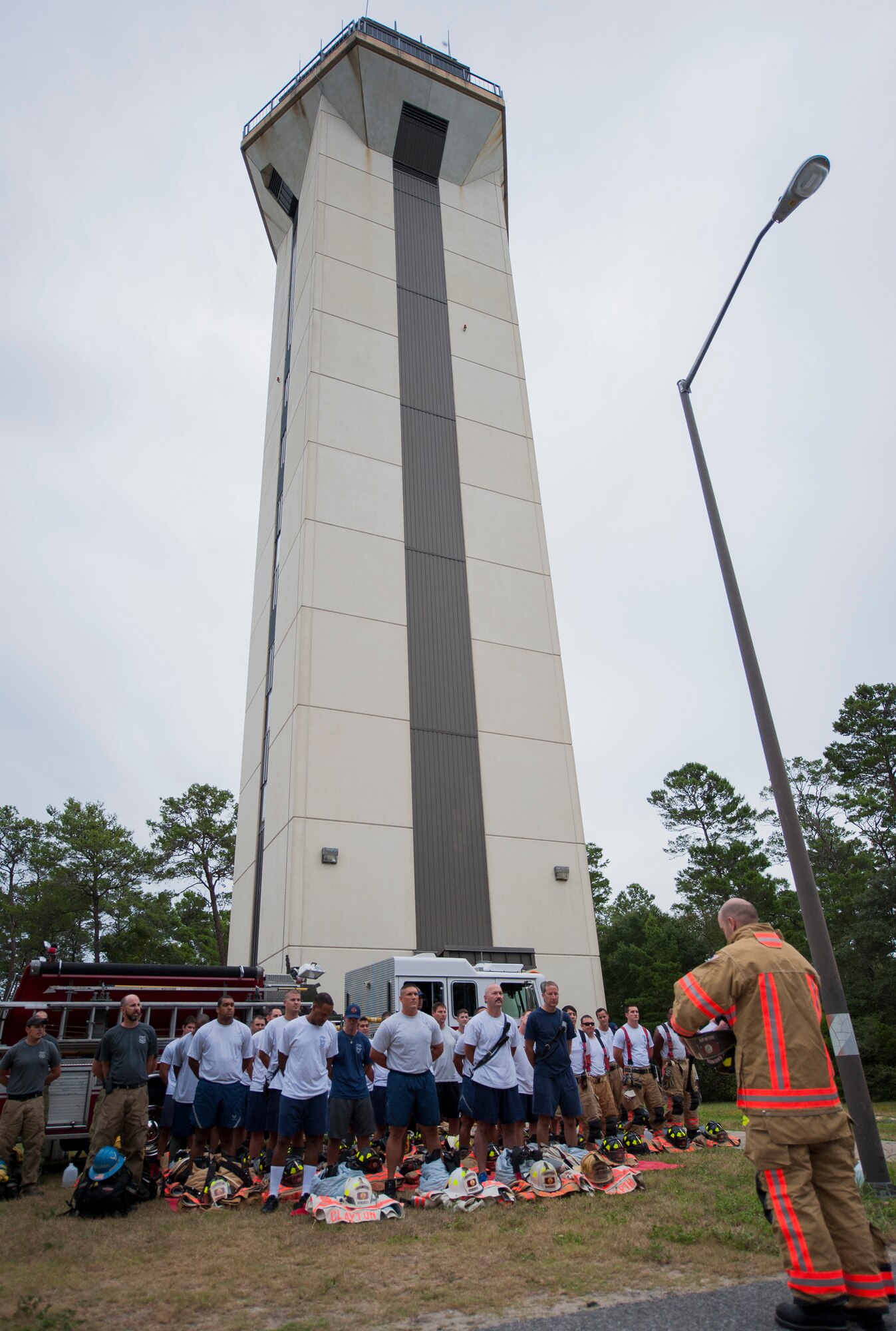 Firefighters from the 96th Civil Engineer Squadron, stand in formation during the annual 9/11 memorial tower climb at Eglin Air Force Base, Fla. Sept. 11. Approximately 45 firefighters climbed 13 flights of steps with a name tag for each of the 343 firefighters who lost their lives 14 years ago. After reaching the top of the air traffic control tower, each name was recited and attached to a commemorative display board. The event closed with traditional bell rings and pauses between each ring to honor the 9/11 heroes. (U.S. Air Force photo/Ilka Cole) 