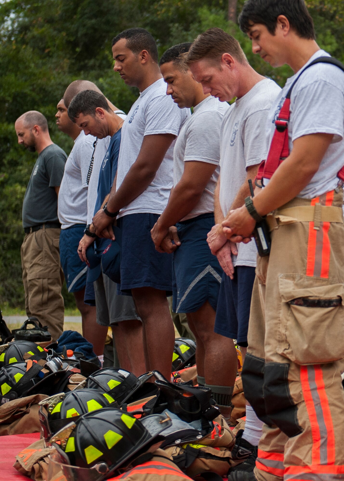 Firefighters from the 96th Civil Engineer Squadron, bow their heads during the annual 9/11 memorial tower climb at Eglin Air Force Base, Fla. Sept. 11.  Approximately 45 firefighters climbed 13 flights of steps with a name tag for each of the 343 firefighters who lost their lives 14 years ago. After reaching the top of the air traffic control tower, each name was recited and attached to a commemorative display board. The event closed with traditional bell rings and pauses between each ring to honor the 9/11 heroes. (U.S. Air Force photo/Ilka Cole)