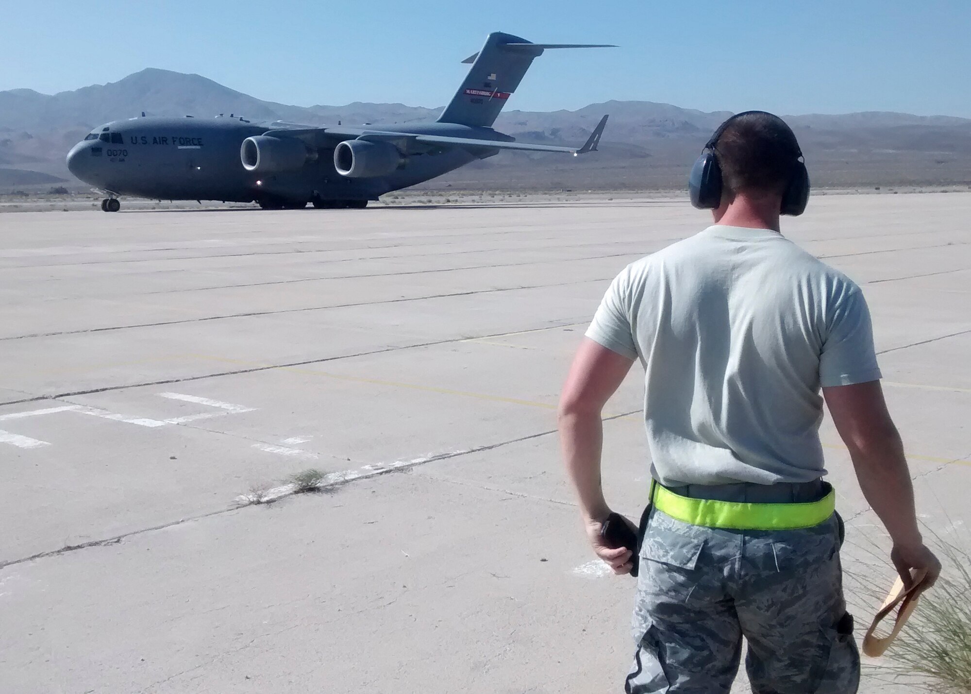 Air Trans Airman Staff Sgt. Andrew Chilcoat, 412th Logistics Readiness Squadron, watches as a C-17 arrives at Barstow-Dagget Airport to transport an Army National Guard Blackhawk helicopter back to the East Coast. (U.S. Air Force photo by Rebecca Amber)