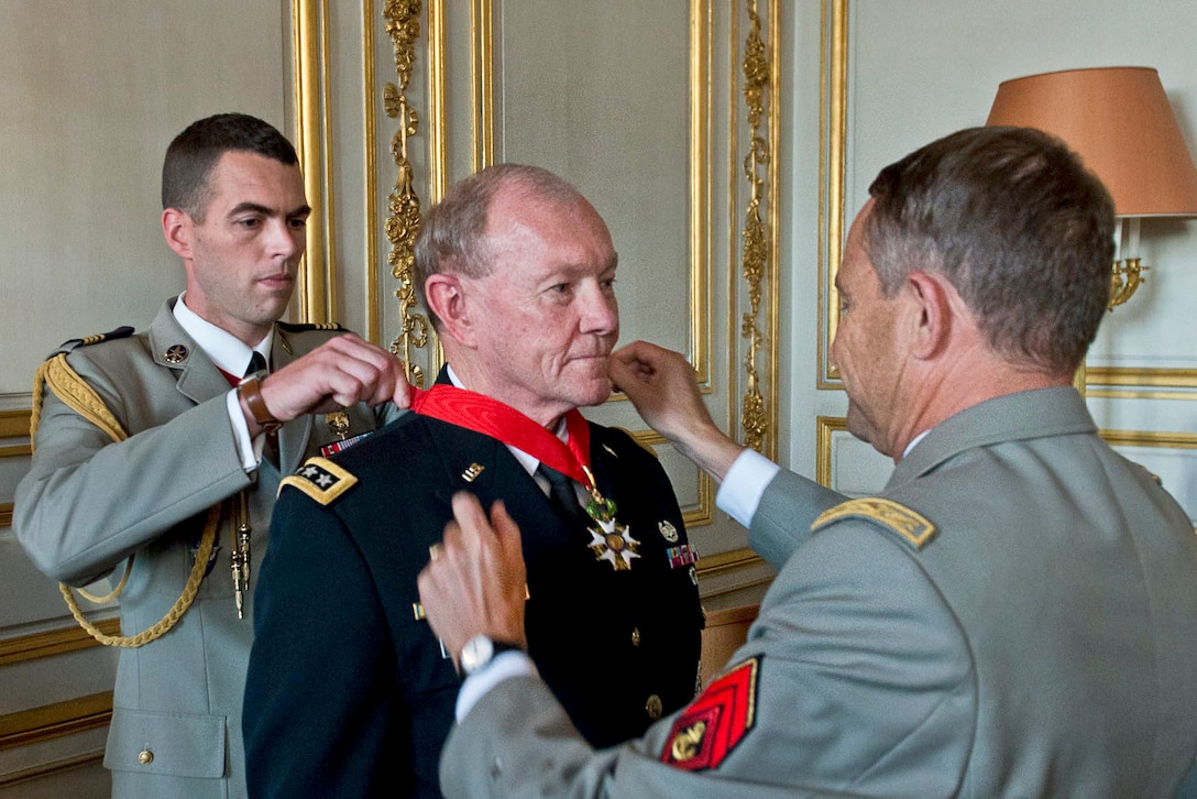French Army Gen. Pierre de Villiers, foreground, chief of defense staff, helps place the French Legion of Honor medal on U.S. Army Gen. Martin E. Dempsey, center, chairman of the Joint Chiefs of Staff, in Paris, Sept. 18, 2014. The medal, established by Napoleon Bonaparte in1802, is the highest decoration in France. DoD photo by D. Myles Cullen