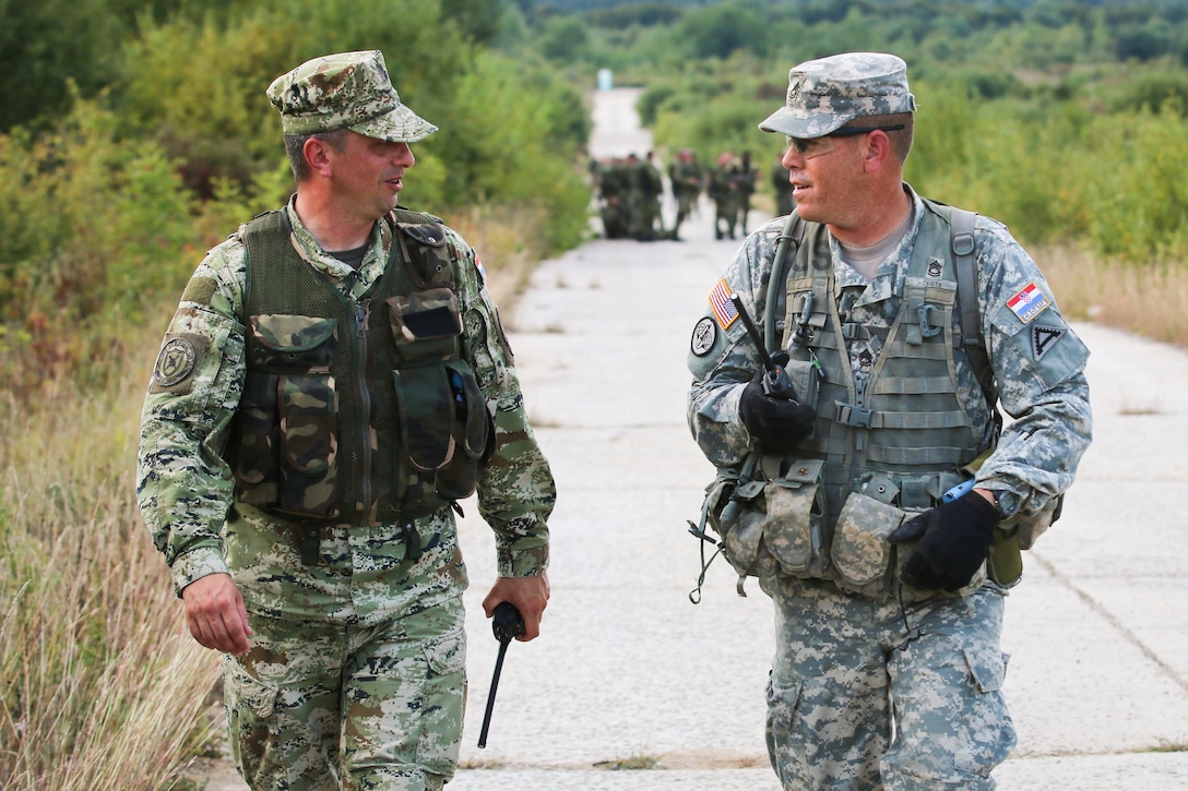 A Croatian soldier and American observer coach trainer walk together after the completion of situational training during Immediate Response 15 in Slunj, Croatia, Sept. 15, 2015. Immediate Response 15 is a multinational, brigade-level, command post exercise utilizing computer-assisted simulations and field training exercises in Croatia and Slovenia. U.S. Army photo by Sgt. 1st Class Caleb Barrieau
