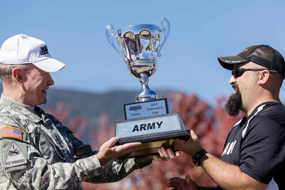 Army Gen. Martin E. Dempsey, chairman of the Joint Chiefs of Staff, presents the Chairman's Cup trophy to Army team captain Frank Barroquiero during the Warrior Games tailgate celebration at the U.S. Air Force Academy in Colorado Springs, Colo., Oct. 4, 2014. The top overall performing service branch receives the trophy. The Army team broke the Marines four-year streak of winning this award. DoD photo by U.S. Army Staff Sgt. Sean K. Harp
