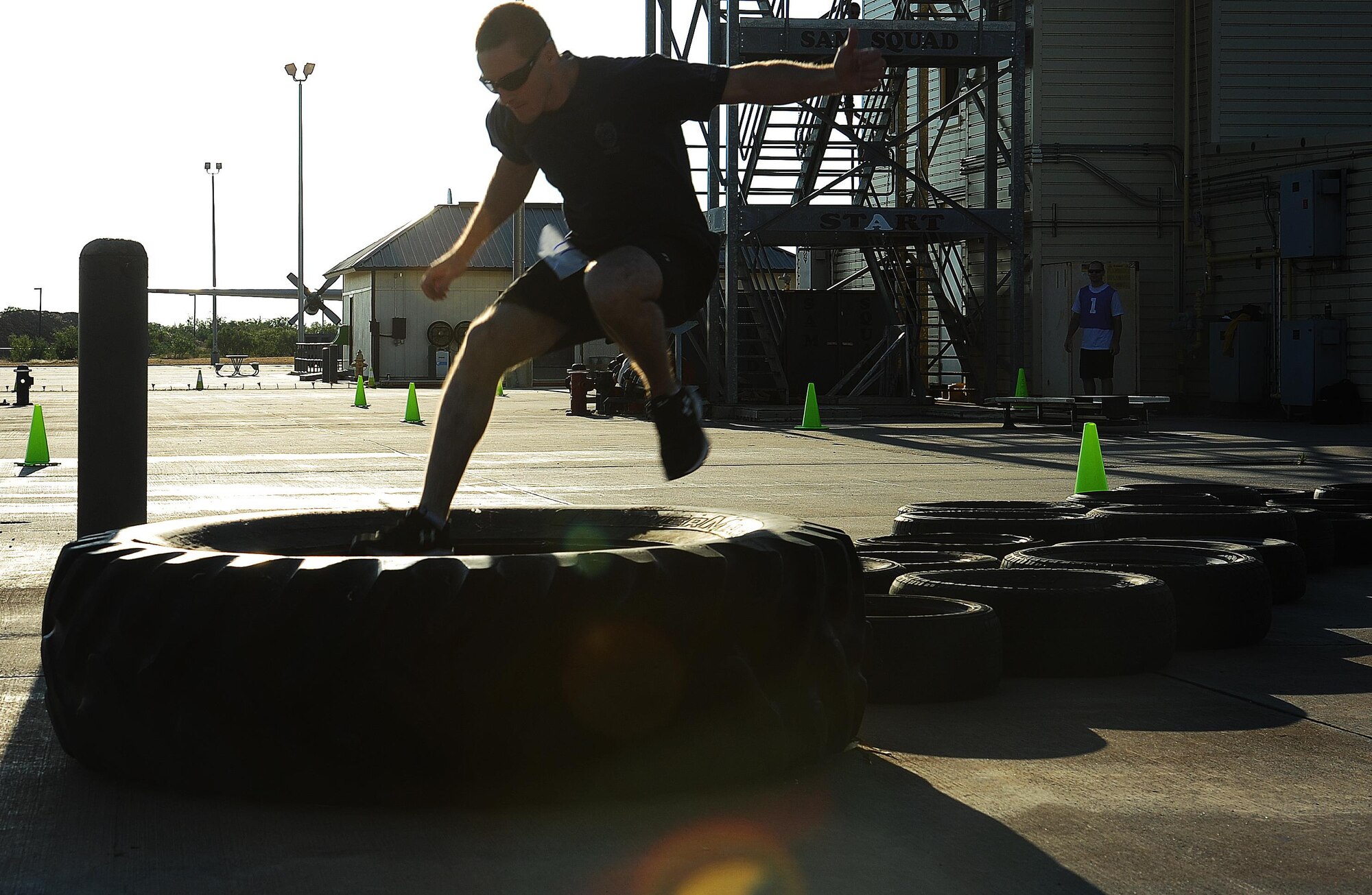 Josh Jones, San Angelo SWAT patrol officer, leaps through the final stretch of the tire run obstacle during the Blood, Sweat and Stairs Competition at Goodfellow Air Force Base, Sept. 12, 2015. The competition included a variety of high intensity leg workouts between climbing multiple staircases. (U.S. Air Force photo by Airman Caelynn Ferguson/Released)