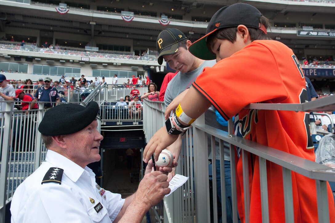 Army Gen. Martin E. Dempsey, chairman of the Joint Chiefs of Staff, signs a baseball for a child during the game between the Washington Nationals and San Fransisco Giants at Nationals Park in Washington, D.C., July, 4, 2015. DoD photo by U.S. Navy Petty Officer 1st Class Daniel Hinton