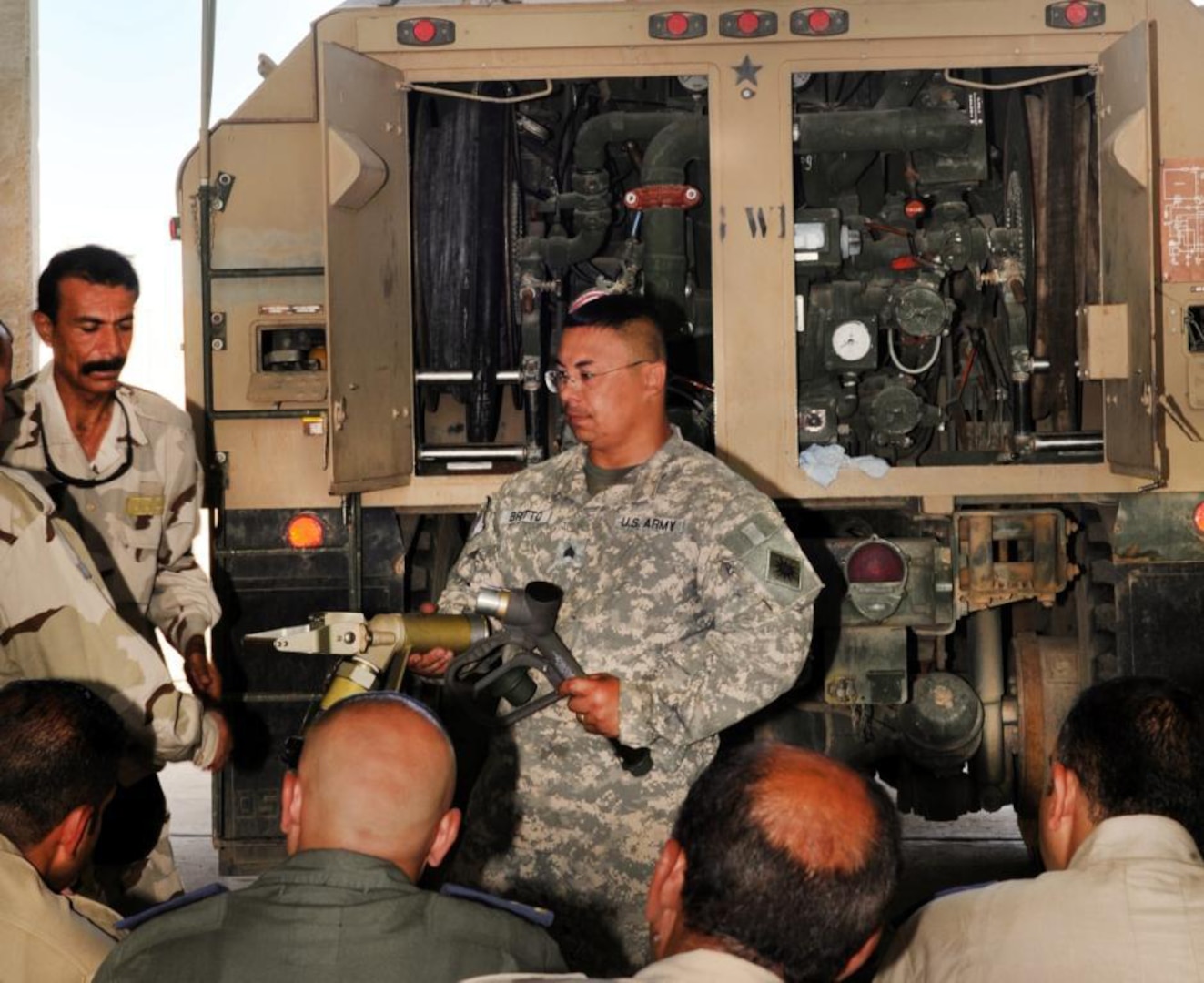 Army Sgt. Gilbert Britto of the California National Guard's Alpha Company, 640th Aviation Support Battalion, shows a class of Iraqi army personnel how to connect a fueling nozzle to the fueling module on a Heavy Expanded Mobility Tactical Truck at Camp Taji, Iraq, Sept. 13, 2011. The 640th conducted a weeklong course for the Iraqi Security Forces to prepare them to take over fueling operations once the California Guard unit departs theater.