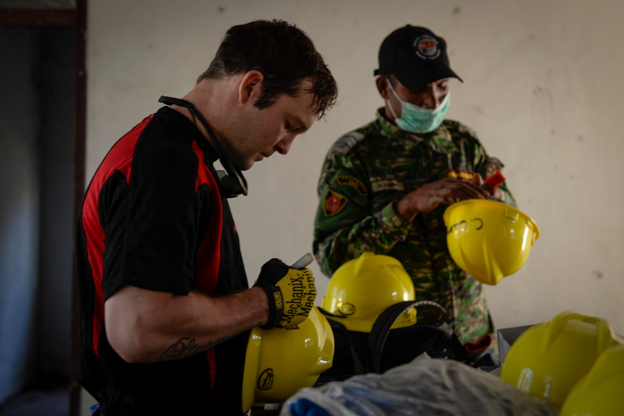 Sapper Reece Stairmand, a Pacific Angel 15-2 carpenter from New Zealand, and a member of the Falintil Forças de Defesa de Timor-Leste, write their names on protective helmets before beginning work on a Pacific Angel 15-2 construction project Sept. 5, 2015, in Baucau, Timor-Leste. Efforts undertaken during Pacific Angel help multilateral militaries in the Pacific improve and build relationships across a wide spectrum of civic operations, which bolsters each nation’s capacity to respond and support future humanitarian assistance and disaster relief operations. (U.S. Air Force photo by Staff Sgt. Alexander W. Riedel/Released)