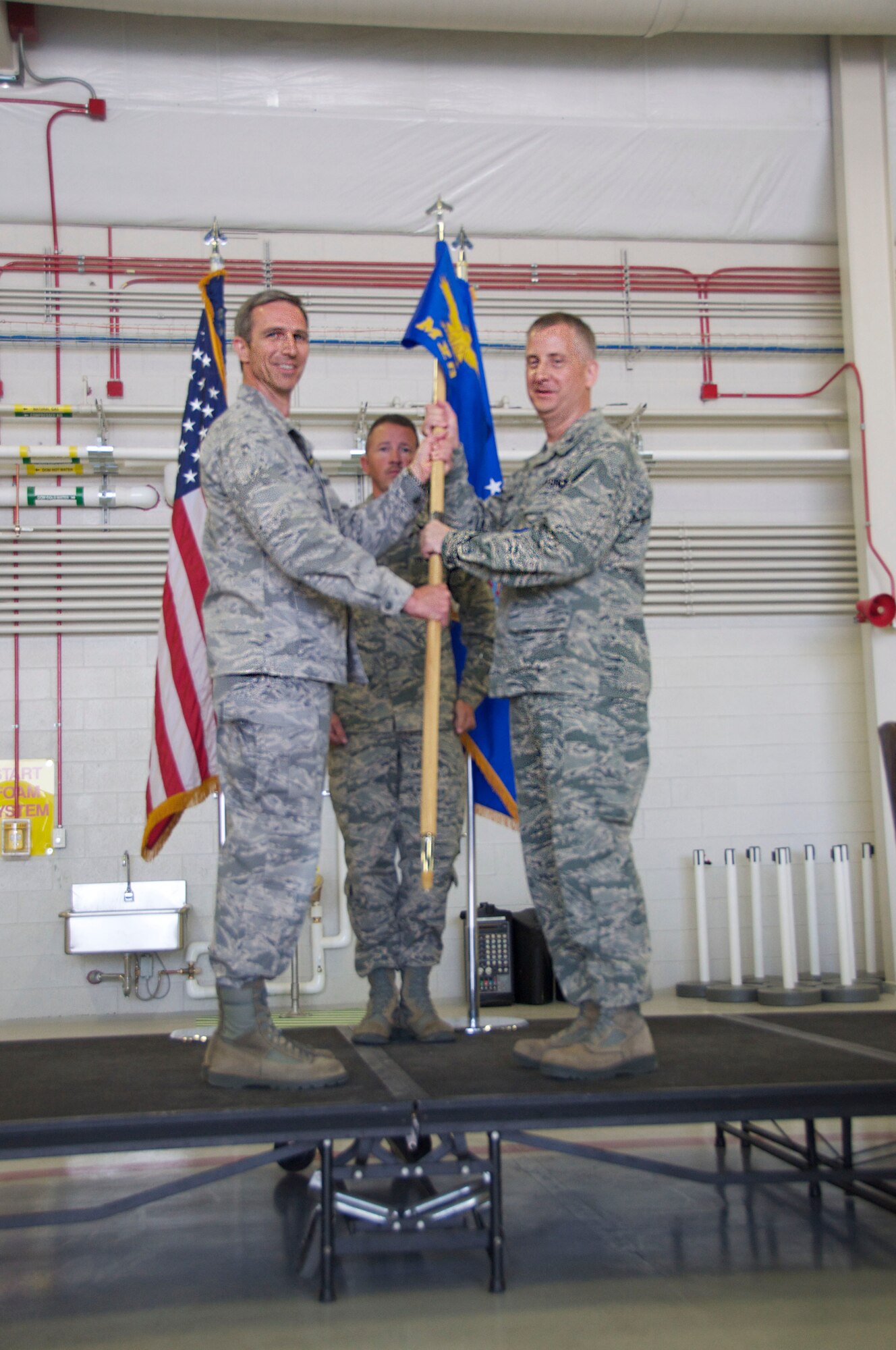 Col. Bryan Radliff, 419th Fighter Wing commander, passes the flagship to Col. Brett Newman, the new 419th Maintenance group commander, during a ceremony here Sunday. (U.S. Air Force photo/Senior Airman Crystal Charriere) 