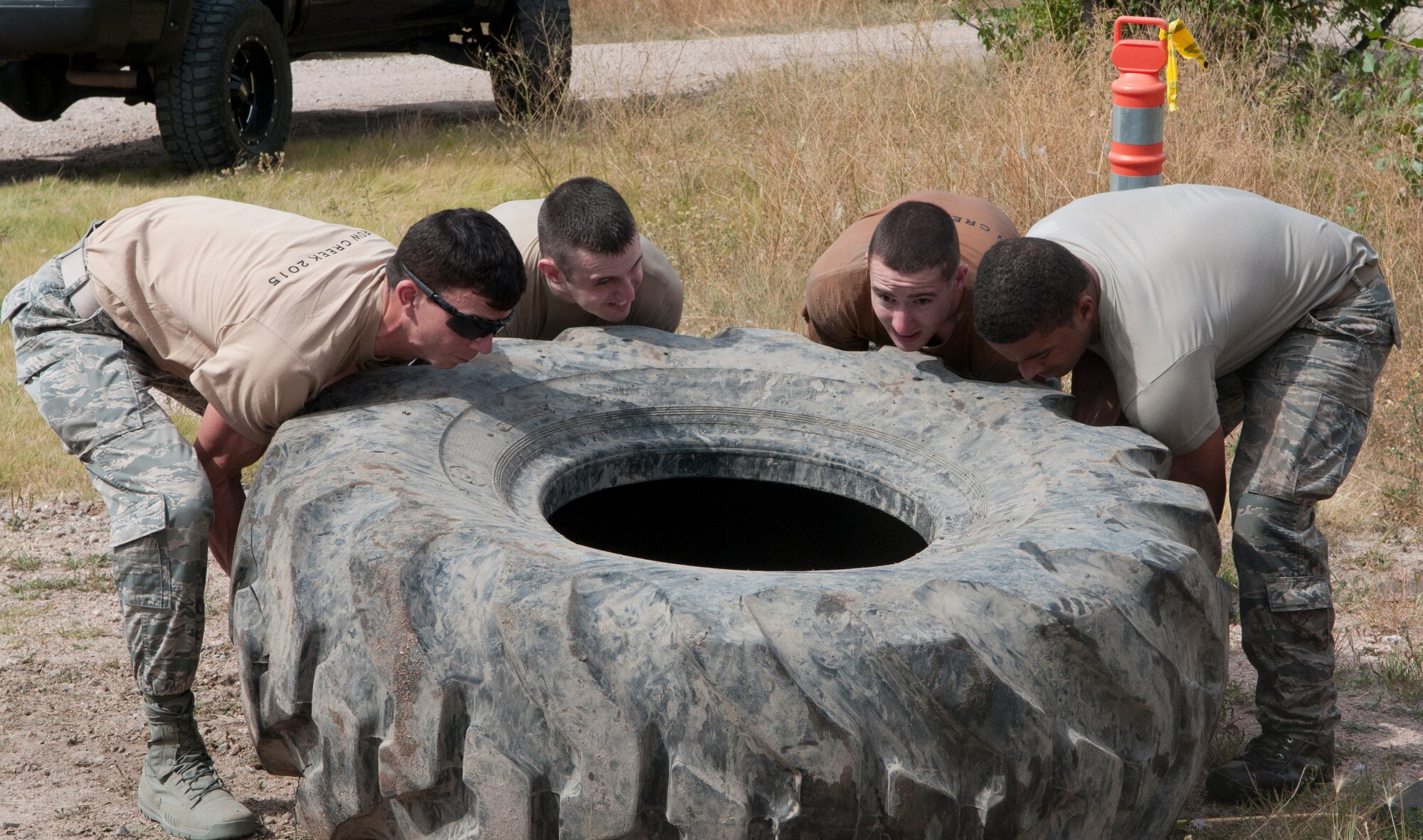 Airmen work together to flip a tire during the Team Pain portion of the 2015 Crow Creek Challenge, Sept. 11, 2015, on F.E. Warren Air Force Base, Wyo. This event consisted of five four-man push-ups, a tire flips for 25-meters and a log carry of 25-meters. (U.S. Air Force photo by Airman 1st Class Malcolm Mayfield)