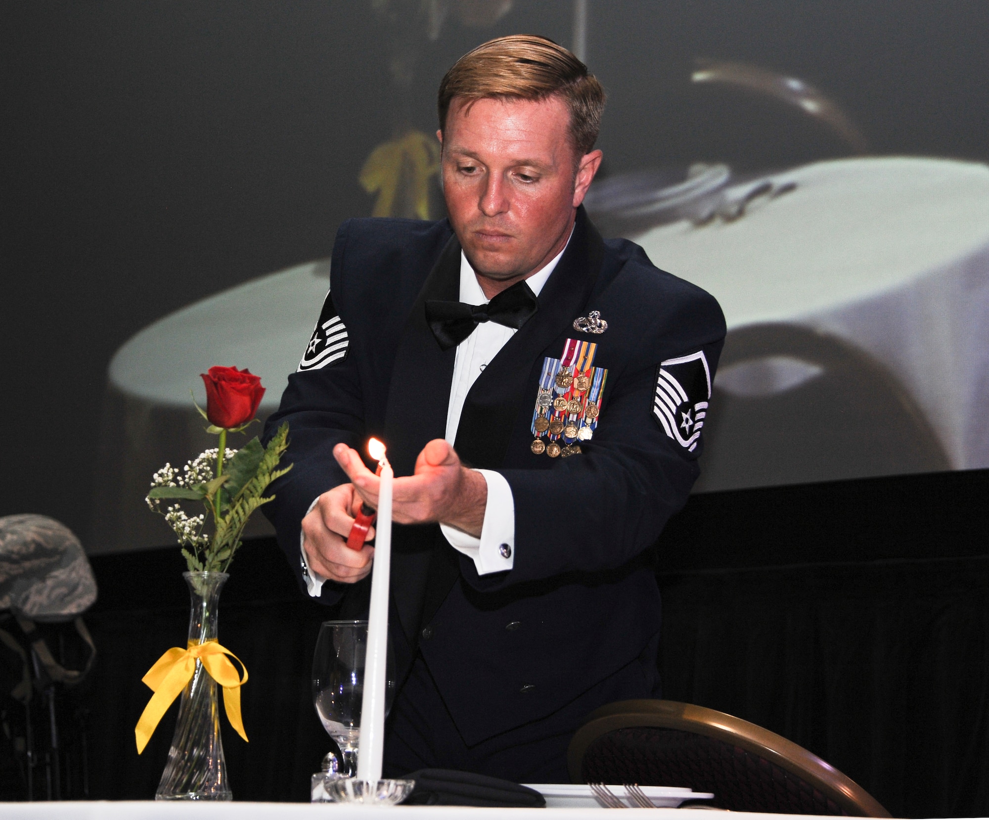 U.S. Air Force Master Sgt. Christopher Cochran, 355th Equipment Maintenance Squadron munition systems section chief, lights a candle at the Missing Man Table during an Air Force Ball at the Tucson Convention Center, in Tucson, Ariz., Sept. 12, 2015. The table is set to honor those killed in action, missing in action, or deployed who could not join in celebration. (U.S. Air Force photo by Airman 1st Class Ashley N. Steffen/Released)  
