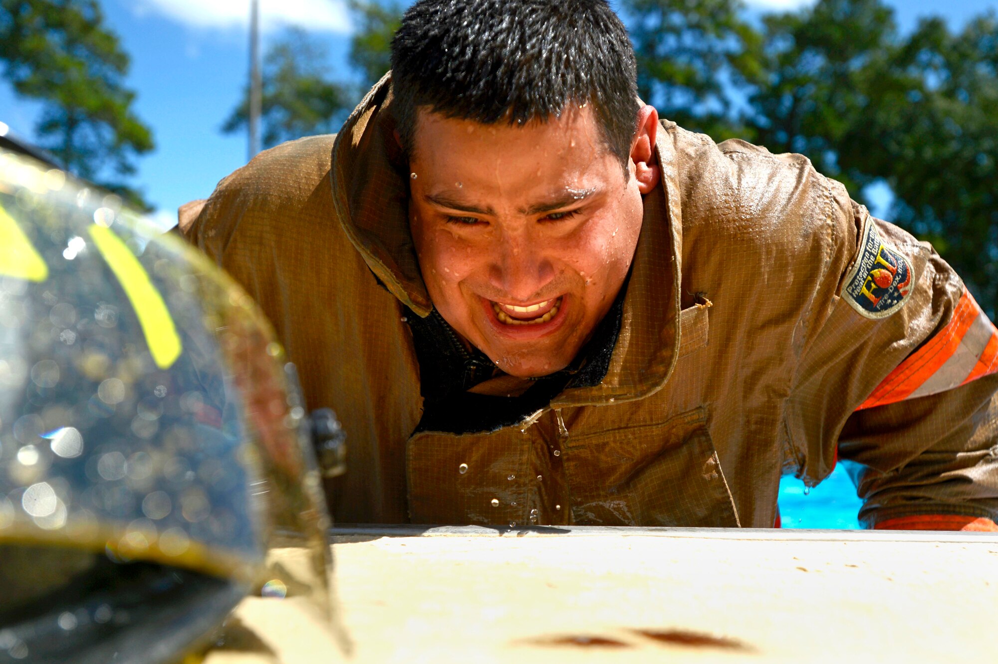 U.S. Air Force Senior Airman Zakaria Mahmoud, 20th Civil Engineer Squadron firefighter, pulls himself out of a pool during firefighter water survival training at Shaw Air Force Base, S.C., Sept. 10, 2015. After completing a correct fall into the water and swimming to the pools edge, Mahmoud pulled himself out of the water with waterlogged turnout gear weighing approximately 200 pounds. (U.S. Air Force photo by Senior Airman Jensen Stidham/Released)