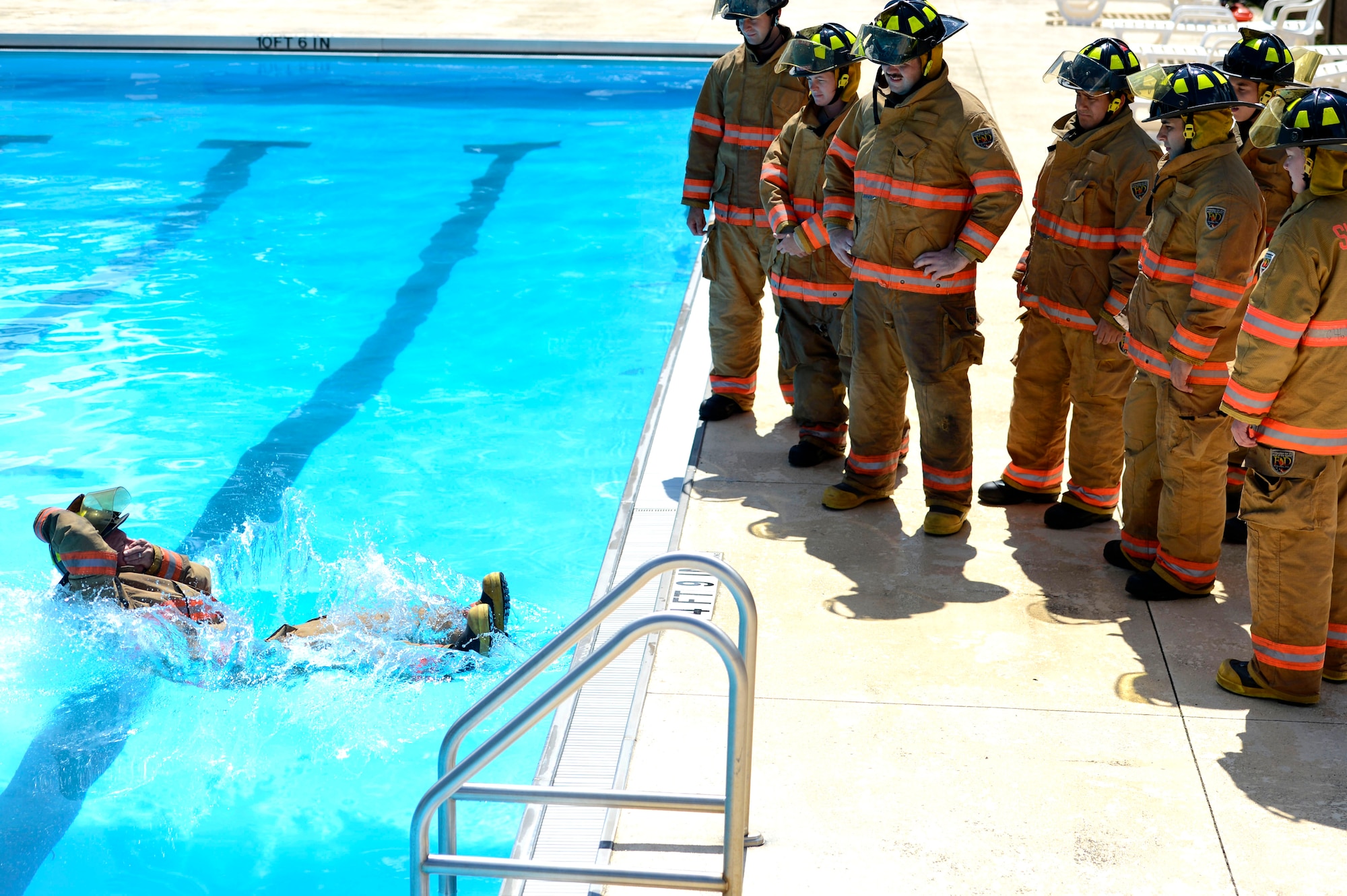 U.S. Air Force firefighters assigned to the 20th Civil Engineer Squadron learn to enter a body of water while wearing turnout gear during firefighter water survival training at Shaw Air Force Base, S.C., Sept 10, 2015. Before entering the water, Airmen learned to fall back-first while holding their helmets in place. (U. S. Air Force photo by Senior Airman Jensen Stidham/Released) 