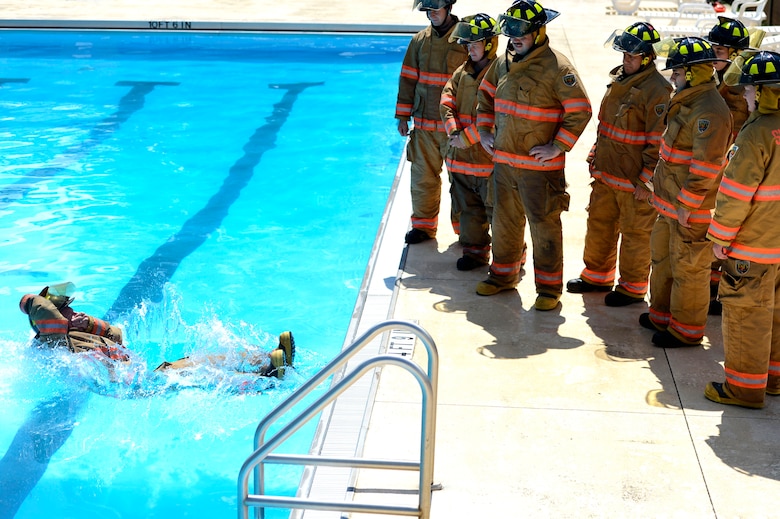 U.S. Air Force firefighters assigned to the 20th Civil Engineer Squadron learn to enter a body of water while wearing turnout gear during firefighter water survival training at Shaw Air Force Base, S.C., Sept 10, 2015. Before entering the water, Airmen learned to fall back-first while holding their helmets in place. (U. S. Air Force photo by Senior Airman Jensen Stidham/Released) 