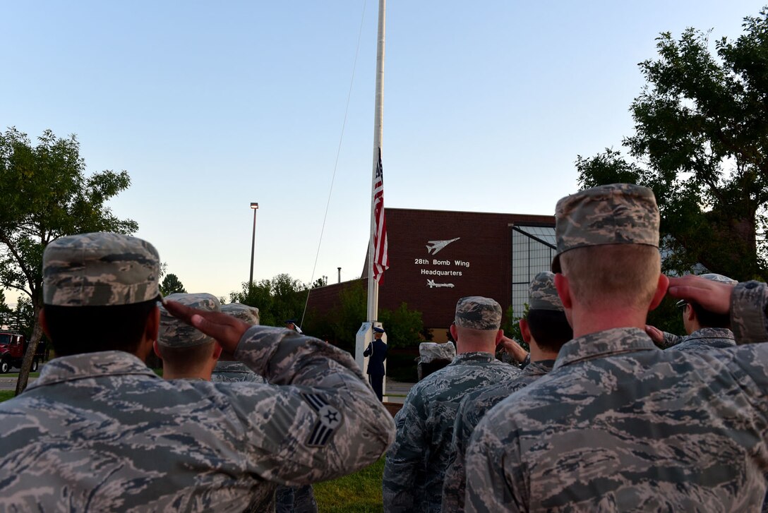 Airmen render a salute during the lowering of the flag at a 9/11 Memorial Ceremony at Ellsworth Air Force Base, S.D., Sept. 11, 2015. It was a day of remembrance and reflection on all of the innocent lives that were lost, but never forgotten. (U.S. Air Force photo by Airman 1st Class James L. Miller/Released)