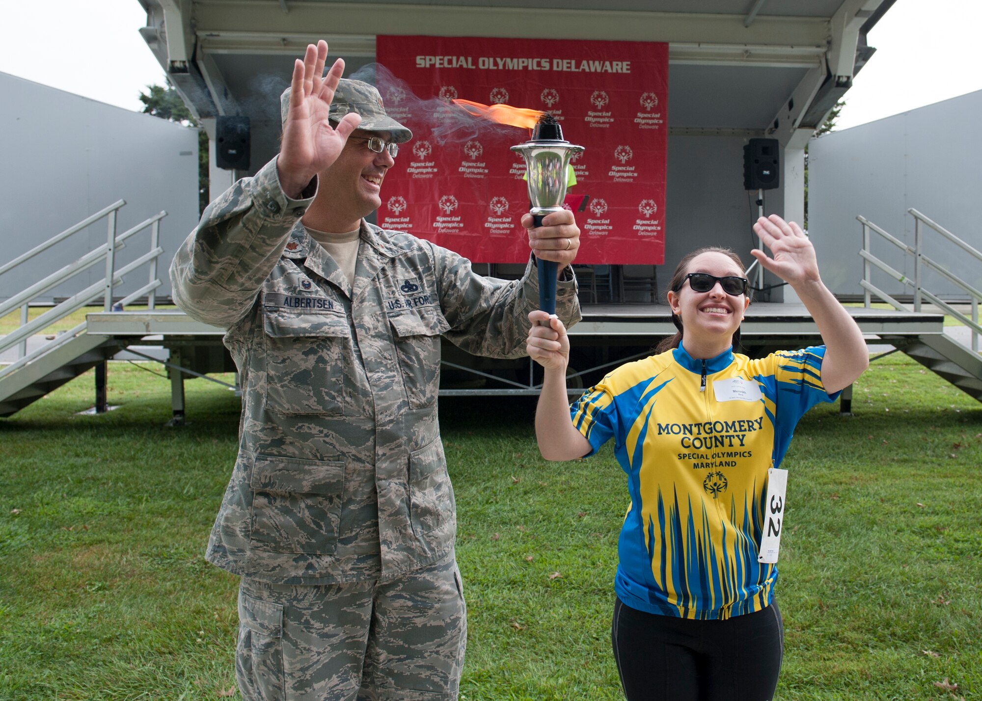 Maj. Danzel Albertsen, 436th Aircraft Maintenance Squadron commander, presents the Olympic torch to Meredith Beck, Team Montgomery County cyclist, at the 2015 Special Olympics Cycling Classic Sept. 12, 2015, at Dover Air Force Base, Del. Beck travelled with her team from Rockville, Md. to compete. (U.S. Air Force photo/Airman 1st Class Zachary Cacicia)