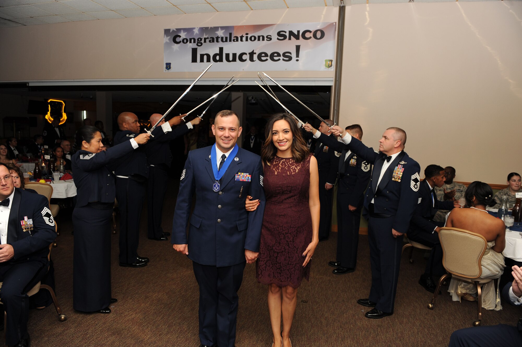 TSgt Brian Edwards, 705th Munitions Squadron, walks under a saber arch with his wife at the Senior Non-Commissioned Officer Induction Ceremony at Minot Air Force Base, N.D., Sept. 11, 2015. This event celebrated the ascension of 52 enlisted personnel into the SNCO tier. (U.S. Air Force photo/Senior Airman Kristoffer Kaubisch)