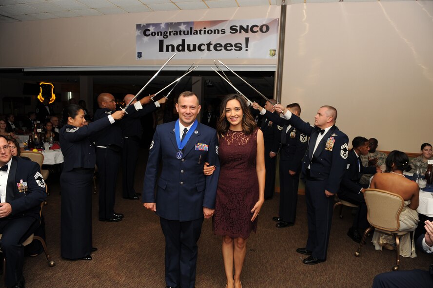 TSgt Brian Edwards, 705th Munitions Squadron, walks under a saber arch with his wife at the Senior Non-Commissioned Officer Induction Ceremony at Minot Air Force Base, N.D., Sept. 11, 2015. This event celebrated the ascension of 52 enlisted personnel into the SNCO tier. (U.S. Air Force photo/Senior Airman Kristoffer Kaubisch)