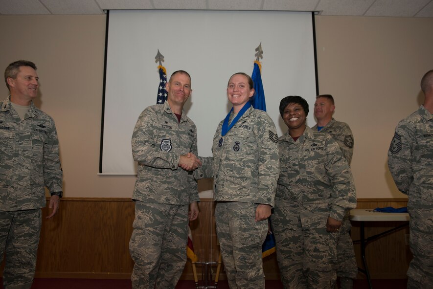 Col. Michael Lutton, 91st Missile Wing commander, presents Technical Sgt. Elizabeth Corp, 91st Missile Security Forces Squadron with a medallion before the Non-Commissioned Officer Induction Ceremony at Minot Air Force Base, N.D., Sept. 11, 2015. This event celebrated the ascension of 52 enlisted personnel into the SNCO tier. (U.S. Air Force photo/ Airman 1st Class Justin Armstrong)