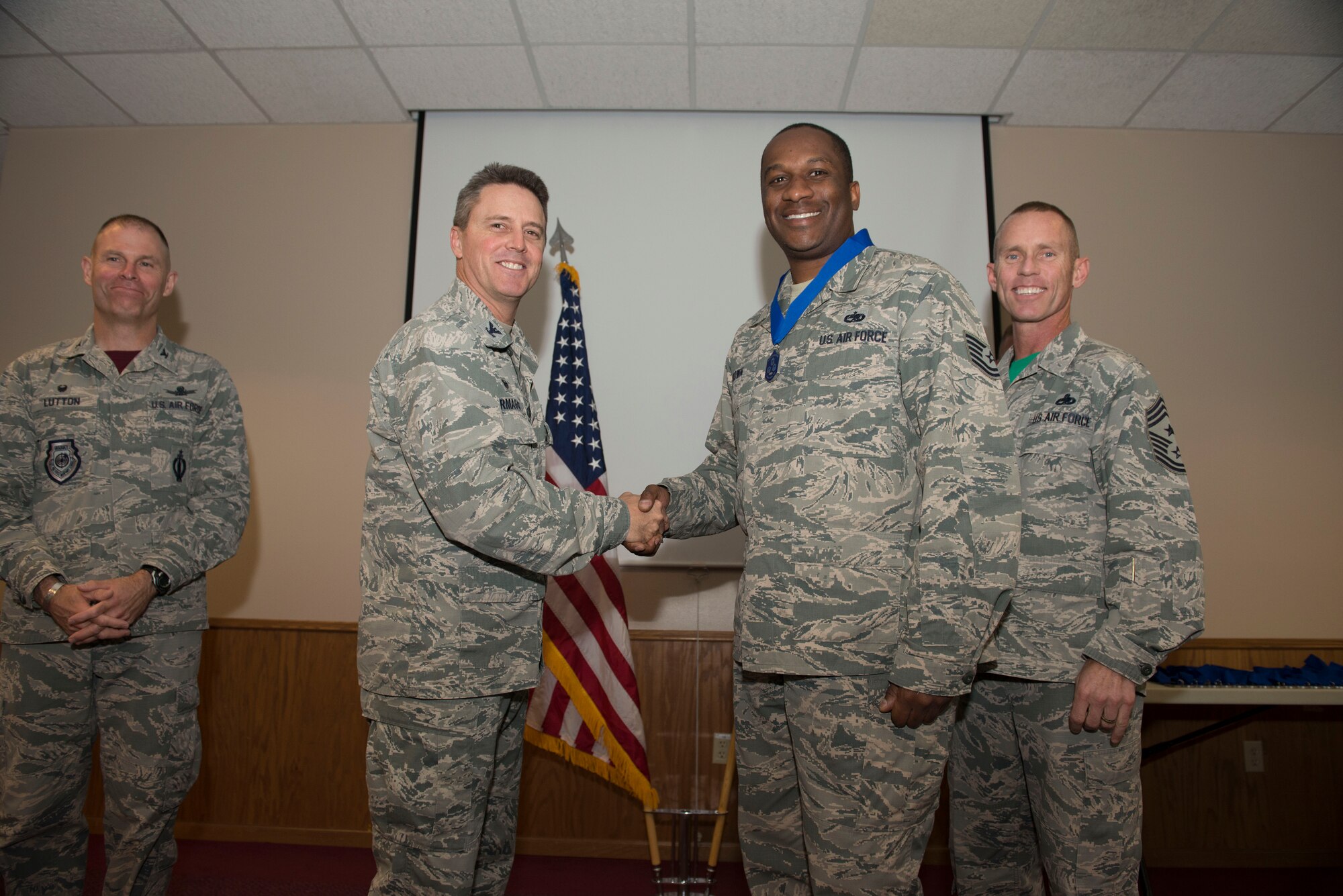 Col. Jason Armogast, 5th Bomb Wing commander, presents Technical Sgt. Kevin Brown, 5th Aircraft Maintenance Operations Squadron with a medallion before the Non-Commissioned Officer Induction Ceremony at Minot Air Force Base, N.D., Sept. 11, 2015. This event celebrated the ascension of 52 enlisted personnel into the SNCO tier. (U.S. Air Force photo/ Airman 1st Class Justin Armstrong)