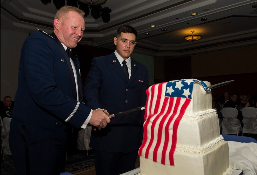 U.S. Air Force Col. Joe McFall, 52nd Fighter Wing commander, left, and U.S. Air Force Airman Basic Omar Chaira, a 52nd Medical Support Squadron outpatient records technician, perform the cake cutting ceremony during the Spangdahlem Air Force Ball at Club Eifel on Spangdahlem Air Base, Germany, Sept. 12, 2015. Both the installation’s most senior-ranking and junior-ranking Airmen cut the cake together as per tradition. (U.S. Air Force photo by Airman 1st Class Luke Kitterman/Released)  
