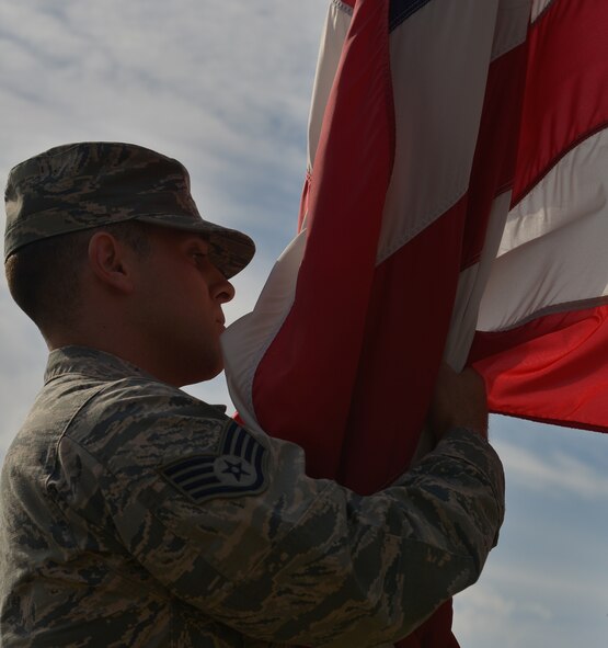 Staff Sgt. Casey Chillemi, 86th Munitions Squadron munitions systems specialist, secures the U.S. flag as it’s lowered during a 9/11 retreat ceremony Sept. 11, 2015, at Ramstein Air Base, Germany. The ceremony paid tribute to those who lost their lives 14 years ago and is held at the same time of day the attacks took place. Members take time to remember the victims of the attacks as well as the sacrifices made by the first responders, who gave their lives to save individuals trapped in the collapsing World Trade Center towers. (U.S. Air Force photo/Airman 1st Class Lane T. Plummer)