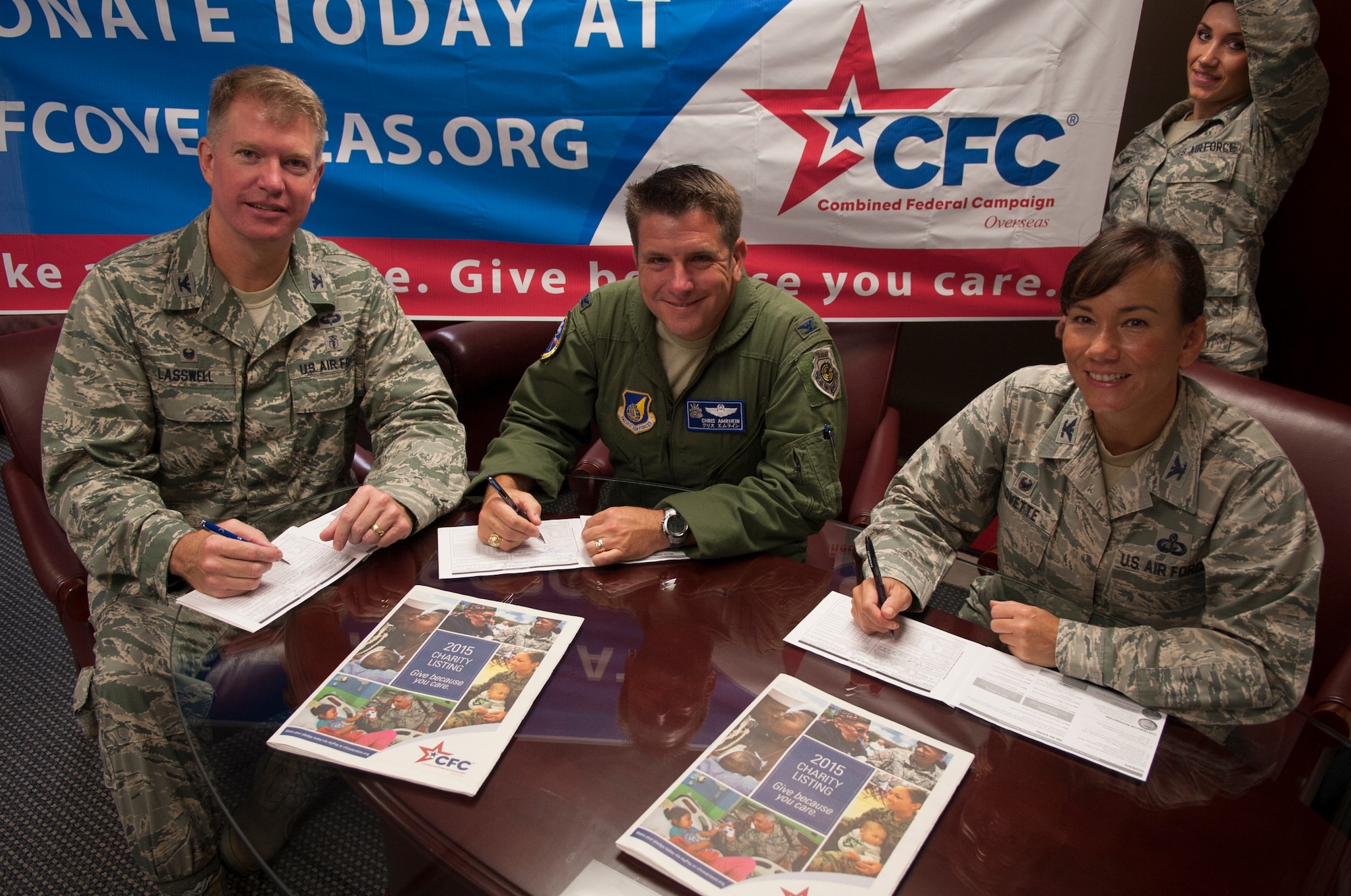 U.S. Air Force Col.l James Lasswell, 18th Medical Group commander,  Col. Christopher Armhein, 18th Wing vice commander,  and Col. Debra Lovette, 18th Mission Support Group commander, sign Combined Federal  Campaign pledge forms, while Airman 1st Class Danielle Clemons holds a CFC- Overseas banner, Sept. 15, 2015 at Kadena Air Base, Japan.  CFC-O is the annual workplace giving campaign for the five overseas combatant commands.  (U.S. Air Force Airman 1st Class Nicholas Emerick)