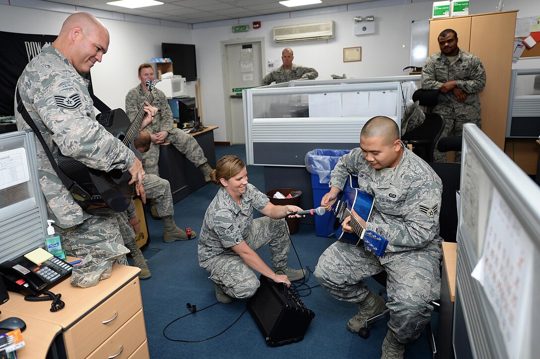 Tech. Sgt. Jason Cale and Senior Airman Melissa Lackore, Air Forces Central Command band members let Airman 1st Class Louis, 380th Expeditionary Contracting Squadron member, take the lead on a song during a performance at an undisclosed location in Southwest Asia, Aug. 26, 2015. The band visited workstations to boost morale of as many Airmen as possible. (U.S. Air Force photo by Staff Sgt. Emerson Nuñez/Released)
