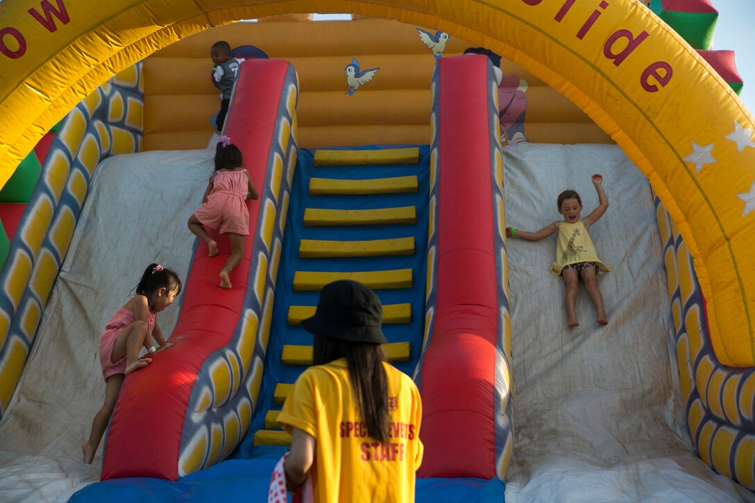 Okinawan children slide down an inflatable slide during HansenFest on Camp Hansen, Okinawa, Japan, Sept. 5, 2015. Hansen Fest is a festival the Marine Corps Community Services organizes to build morale among the Marines as well as relationships with the Okinawan citizens. MCCS is a program that improves the health and welfare of the Marine Corps community.