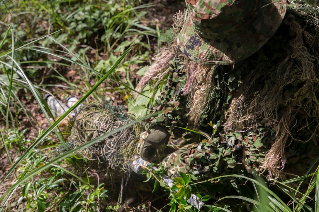 Japanese Ground Self-Defense Force Sgt. Akito Yagi attaches vegetation to his sniper rifle while performing stalking drills during Forest Light 16-1 at Camp Imazu, Takashima, Japan, Sept. 10, 2015. The Marines sat up on a high embankment, trying to catch the JGSDF stalking the target with binoculars. Forest Light is a semiannual, bilateral exercise consisting of a command post exercise and multiple field training events, conducted by elements of III Marine Expeditionary Force and the JGSDF. Yagi is a sniper with 50th Infantry Regiment, 14th Brigade. 