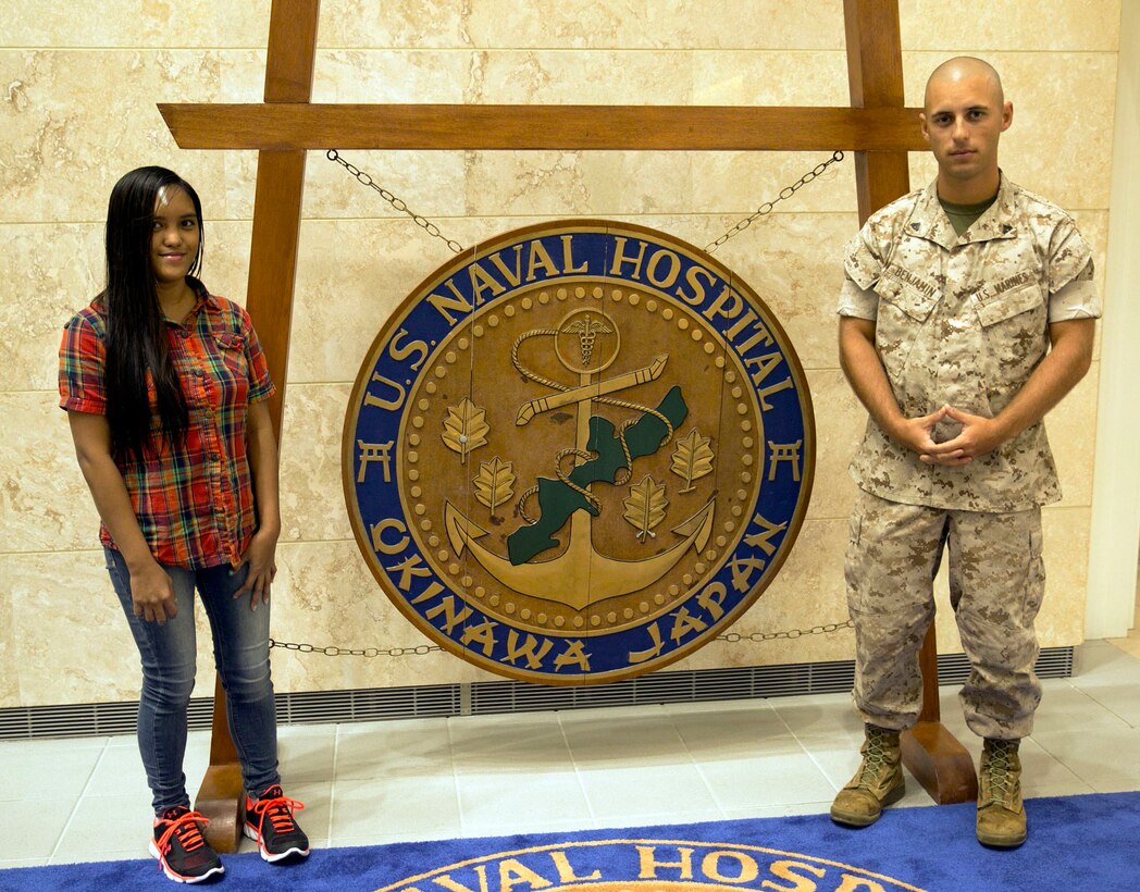 Cpl. Daniel J. Benjamin Jr. poses for a photo with Paula Genova at the U.S. Naval Hospital Okinawa, Camp Foster, Okinawa, Japan, Sept. 14, 2015, two weeks after saving her life from a substantial head injury. On Aug. 31, Paula was riding her bike when she lost control and was struck in the head by a tree branch. After she lost a significant amount of blood and had been screaming for help, Benjamin came to her aid by taking her straight to the hospital. Benjamin recently received a unit challenge coin from the III Marine Expeditionary Force sergeant major, Sgt. Maj. Lee D. Bonar Jr., for his selfless act. Paula is a tourist from Manila, Philippines. Benjamin is a digital wideband repair Marine with Headquarters Marine Wing Support Group 18, Marine Air Control Group 18, 1st Marine Aircraft Wing, III Marine Expeditionary Force.