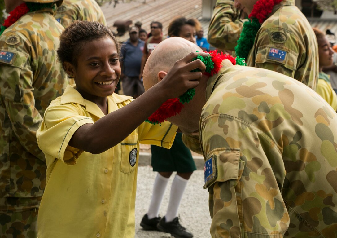 A Papua New Guinea native greets a Royal Australian soldier with a flowered decoration after members from the U.S. Marine Corps, U.S. Navy, Royal Australian Army and Royal British Army arrive at the Taurama Barracks, Papua New Guinea, for exercise Puk Puk 15, Sept 1. The purpose of the exercise is to increase interoperability between multiple nations and exchange engineering tactics. The U.S. Marines and sailors are stationed in Okinawa, Japan. 