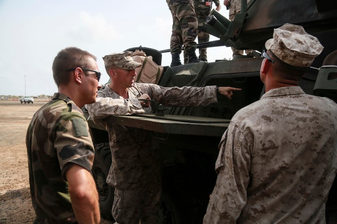 CAMP LEMONNIER, Djibouti (Sept. 9, 2015) U.S. Marine Capt. Thomas Vallely, middle, explains the capabilities of a Light Armored Vehicle (LAV-25). Vallely is the company commander with Delta Company, 1st Light Armored Reconnaissance Detachment, Battalion Landing Team 3rd Battalion, 1st Marine Regiment, 15th Marine Expeditionary Unit. Elements of the 15th MEU are preparing to conduct bilateral training with the 5th Overseas Combined Arms Regiment (RIAOM) in Djibouti in order to improve interoperability between the MEU and the French military. (U.S. Marine Corps photo by Sgt. Steve H. Lopez/Released)