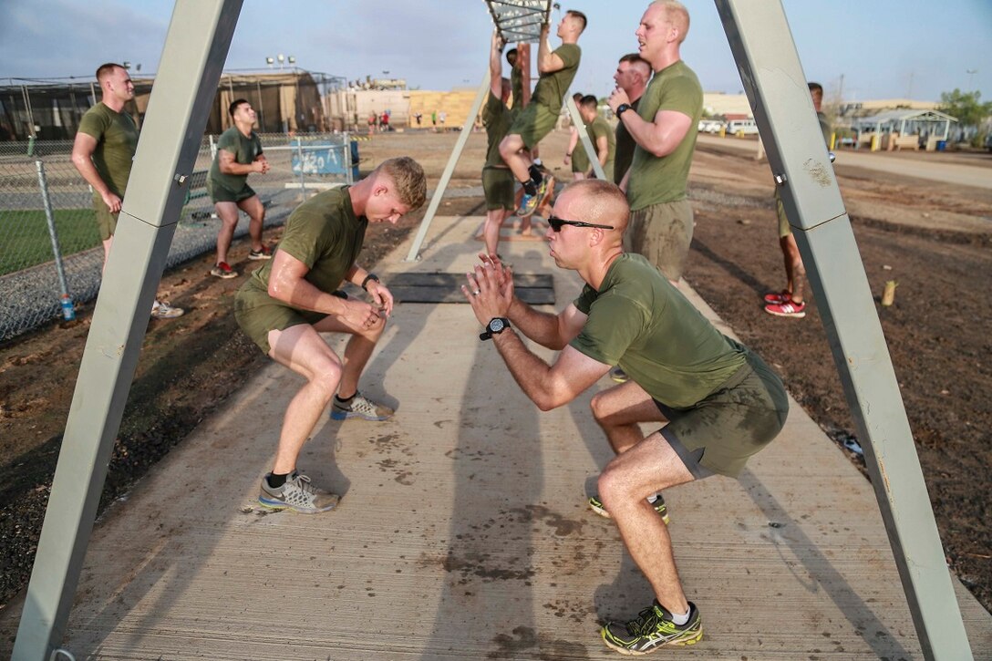 CAMP LEMONNIER, Djibouti (Sept. 11, 2015) U.S. Marine Capt. Pete Hofinga, right, performs squats during unit physical training. Hofinga is the executive officer for Weapons Company, Battalion Landing Team 3rd Battalion, 1st Marine Regiment, 15th Marine Expeditionary Unit. The Marines use unit PT to acclimatize to Djibouti’s temperatures, and stay fit. Elements of the 15th MEU are preparing to conduct bilateral training with the 5th Overseas Combined Arms Regiment (RIAOM) in Djibouti in order to improve interoperability between the MEU and the French military. (U.S. Marine Corps photo by Sgt. Steve H. Lopez/Released)
